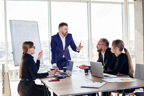 Business people working together in a modern office with cityscape view. The director tells the staff about new technologies. Office work concept