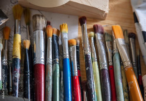 Paintbrushes used with stains on wooden table. Blur over view background.