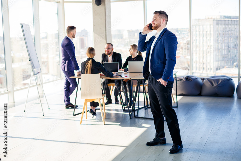 Business people, businessmen are working together in a modern office in a multi-storey skyscraper. The director is on the phone. Office work concept. Selective focus Business people, businessmen are working together in a modern office in a multi-storey skyscraper. The director is on the phone. Office work concept. Selective focus