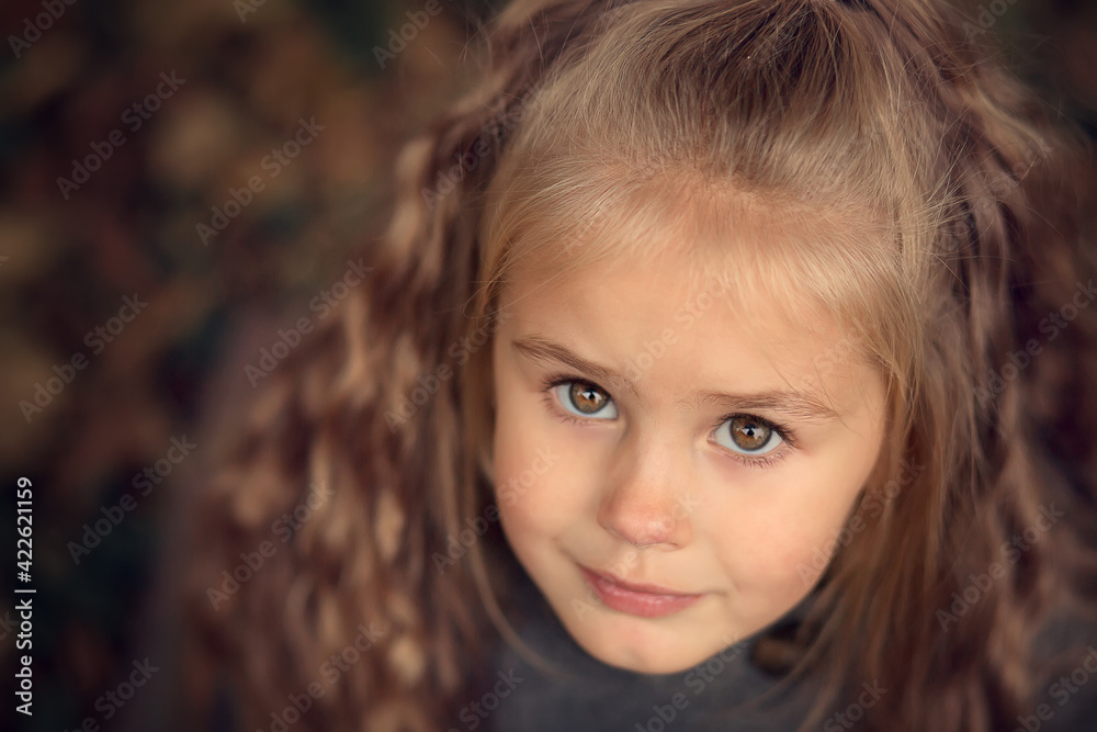 Portrait of beautiful long haired blonde girl in old autumn garden. Image with selective focus and toning. Portrait of beautiful long haired blonde girl in old autumn garden. Image with selective focus and toning.