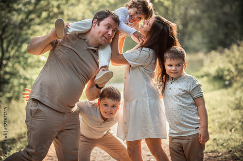 A happy family portrait with parents and their three sons in a sunny day in the park. Image with selective focus and toning