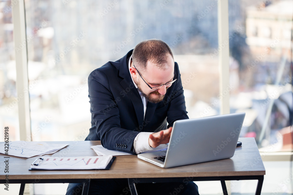 The corporate madman is sitting at the computer in the office and going crazy, the emotional portrait of the man at the table. Crazy worker at his workplace