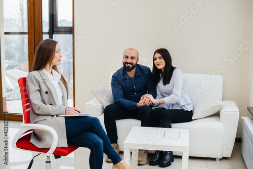 A young happy married couple of men and women talk to a psychologist at a therapy session. Psychology.