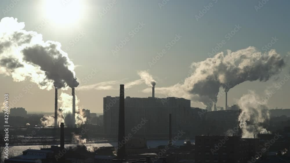Smoke from chimneys in city. Residential buildings, river. Lots of pipes. The sun. Industrial area Smoke from chimneys in city. Residential buildings, river. Lots of pipes. The sun. Industrial area