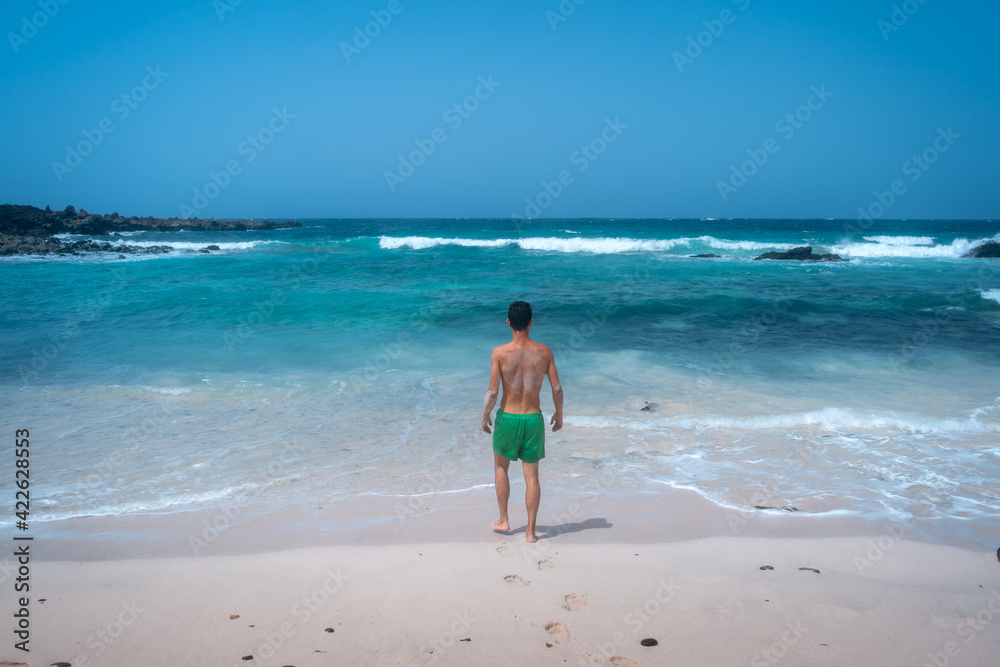 young man on the shore of a white sand beach in Orzola. Lanzarote. Las Palmas. Canary islands