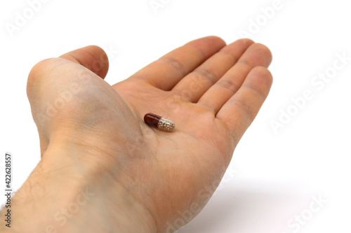 A man holds a pill in his hand, offers help