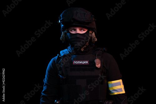 Male in black uniform conforms to Police SWAT. Patch on the back with the inscription Police in Russian. Black background (red and blue lights) photo