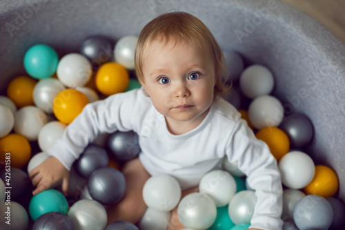 girl child sits in a pool with colorful plastic balls