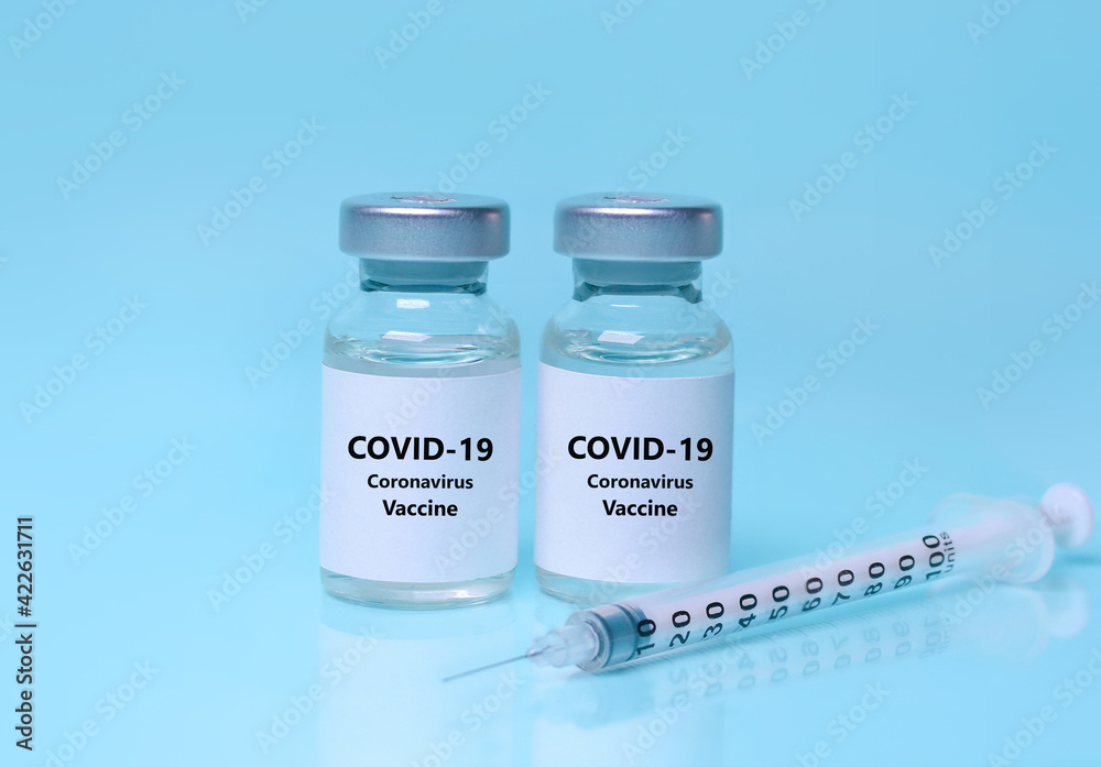 Vaccine in a bottle with a syringe on a blue background. Syringe, two vials (two doses) of coronavirus vaccine.The concept of medicine, healthcare and science.Coronavirus vaccine. Vaccine in a bottle with a syringe on a blue background. Syringe, two vials (two doses) of coronavirus vaccine.The concept of medicine, healthcare and science.Coronavirus vaccine.
