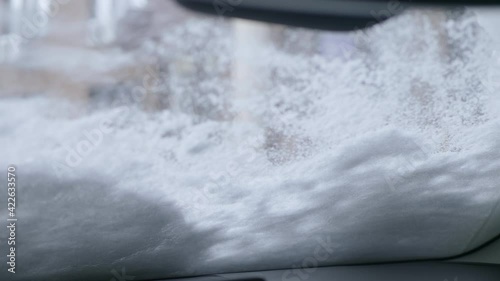 Wipers clean the windshield of the car. Inside blurred view of a city. Driving in difficult weather conditions photo