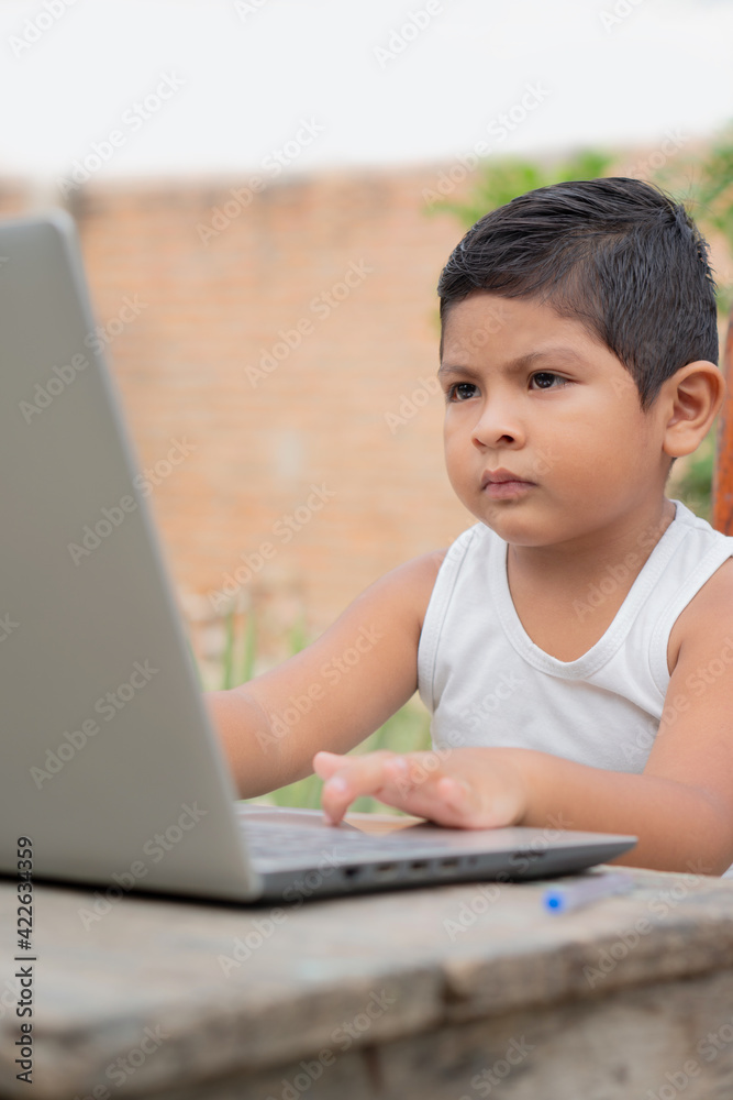 Latino boy using a laptop. Hispanic infant looking at a computer screen. Online education, preschool, new generation. Brunette baby. Little netizen. Latino boy using a laptop. Hispanic infant looking at a computer screen. Online education, preschool, new generation. Brunette baby. Little netizen.