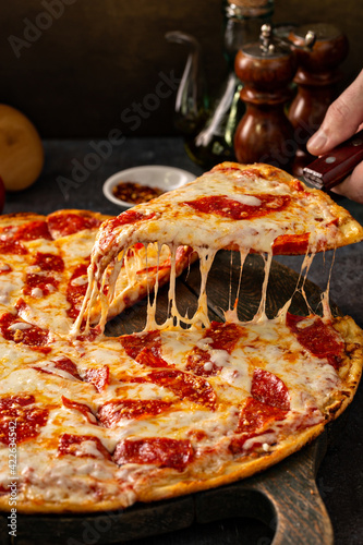 Pepperoni pizza with a slice taken out with cheese pull