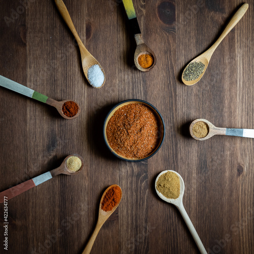 Fototapeta Naklejka Na Ścianę i Meble -  A top down view of a haphazard arrangement of wooden spoons filled with spices used to make a southwest spice blend.