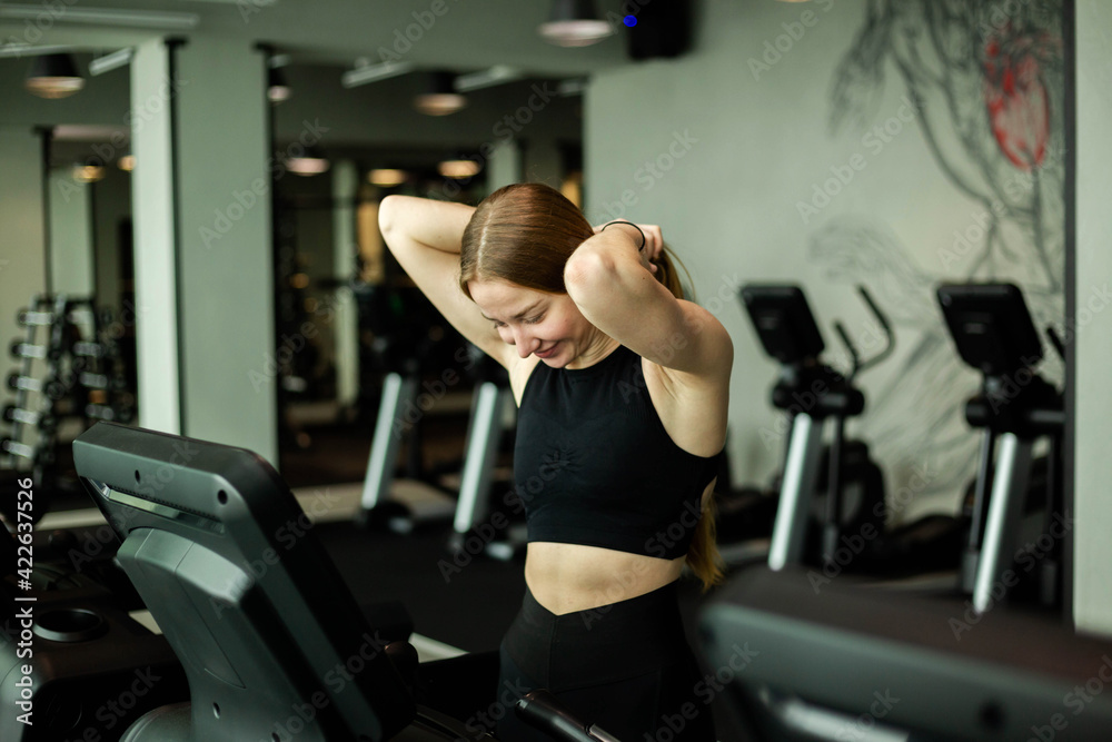 Fototapeta premium Happy athletic woman jogging on treadmills in a gym.