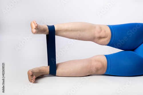 female legs close up. lesson with fitness rubber bands. sport concept. White background. space for text