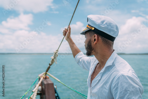 Sailing sport. Captain in charge. Latin american man with ship captain's hat.