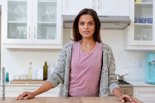 Caucasian woman staning in kitchen looking at camera and smiling photo