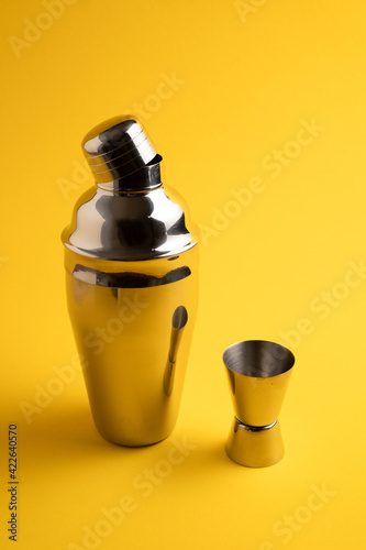 Cocktail shaker kit on yellow background. Cobbler cocktail shaker. Vertical image. Metal cocktail shaker isolated