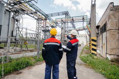 Two specialist electrical substation engineers inspect modern high-voltage equipment. Energy. Industry