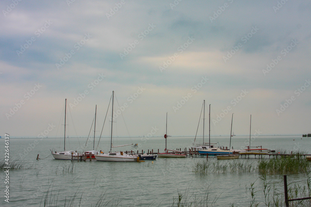 Small sailboats moored on the lake of balaton in hungary on a cloudy summer day.