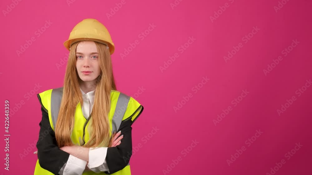 Beautiful woman in reflective vest, yellow hardhat and jacket with crossed hands Beautiful woman in reflective vest, yellow hardhat and jacket with crossed hands