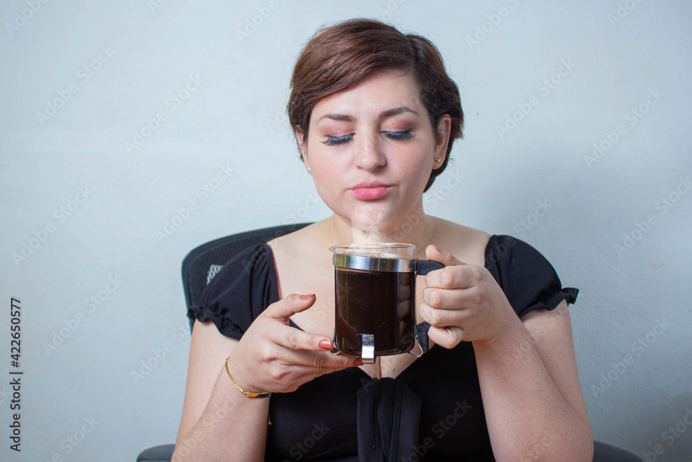 Woman smelling fresh hot coffee in French press with a satisfied face Woman smelling fresh hot coffee in French press with a satisfied face