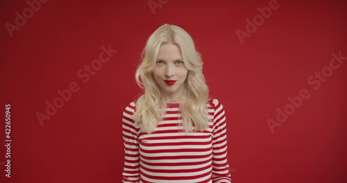 Villain idea. Sly blonde woman conspiring scheming, thinking over tricky plan with cunning expression, pondering revenge or evil prank. Indoor studio shot isolated on red background