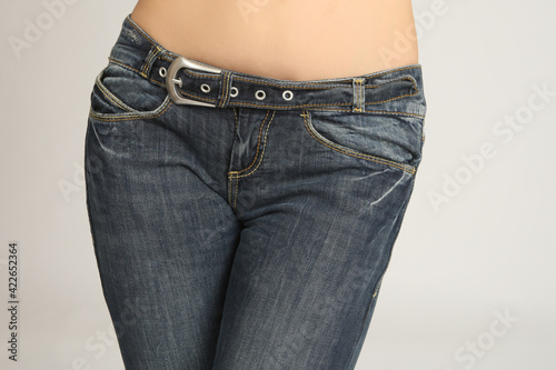 Girl wearing jeans. Close up of a girl thighs in pants. Naked woman in jeans. Devshuka in denim trousers crossed her legs. Concept - advertising of women's clothing. Sale of denim clothes for girls