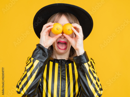 Woman with lemons in her hands. She plays fool by putting lemons to her eyes. Young girl have fun. Girl with lemons on face smiles. Concept - sale of citrus fruits. Fresh fruit sale photo