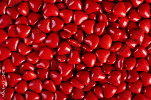 Photos Top view of red heart-shaped candies in a container under the lights