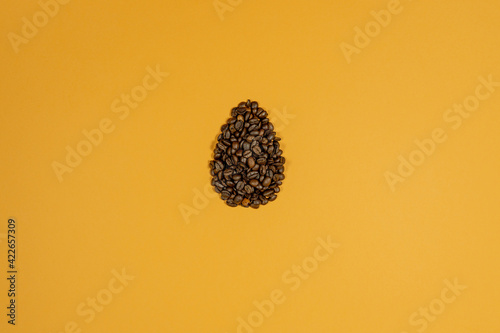 Egg shaped fresh coffee beans. Yellow background. Creative eastern or coffee background