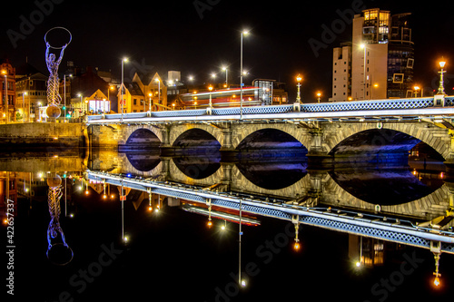 Queen's Bridge in Belfast, Northern Ireland. Long exposure of night cityscape of illuminated bridge with a bus passing through..