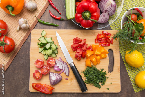 Different vegetables for cooking healthy diet food. Cutting vegetable and greens for salad on wooden board on kitchen photo