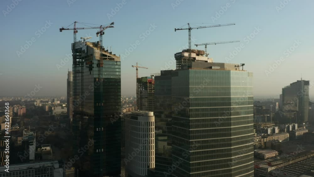 Construction of skyscrapers in the business center of Warsaw in 2020. Drone shot at dawn into skyscrapers with construction cranes at dawn.Warsaw, Poland. Construction of skyscrapers in the business center of Warsaw in 2020. Drone shot at dawn into skyscrapers with construction cranes at dawn.Warsaw, Poland.