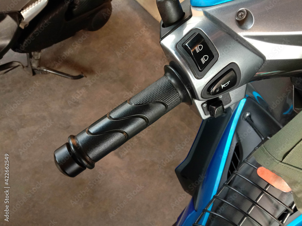 Motorcycle left handle bar with lights switch and horns parked on the car park closeup. Motorcycle left handle bar with lights switch and horns parked on the car park closeup.