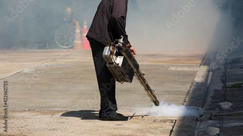 Man pointing smoke machine into manhole for pest control photo