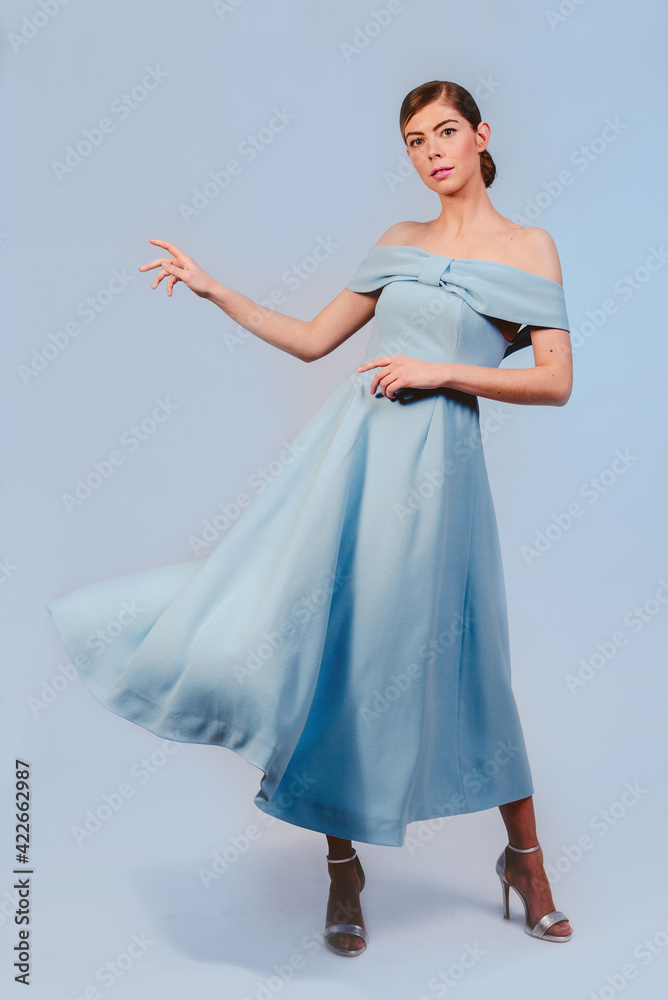 Naklejka premium full shot of blonde young girl in blue dress on blue background