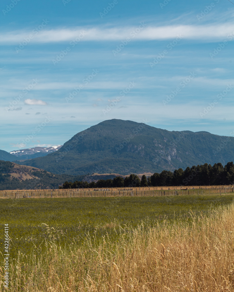 Fototapeta premium Día soleado en el campo con montes de fondo.