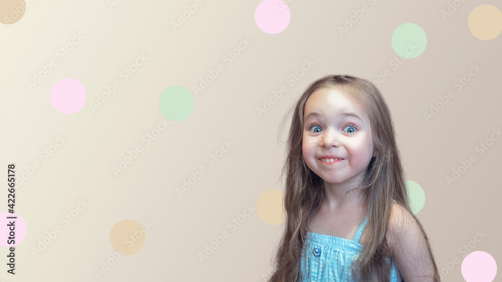 The baby girl stands with loose, thick long hair, looking surprised and smiling. Background with colored circles.