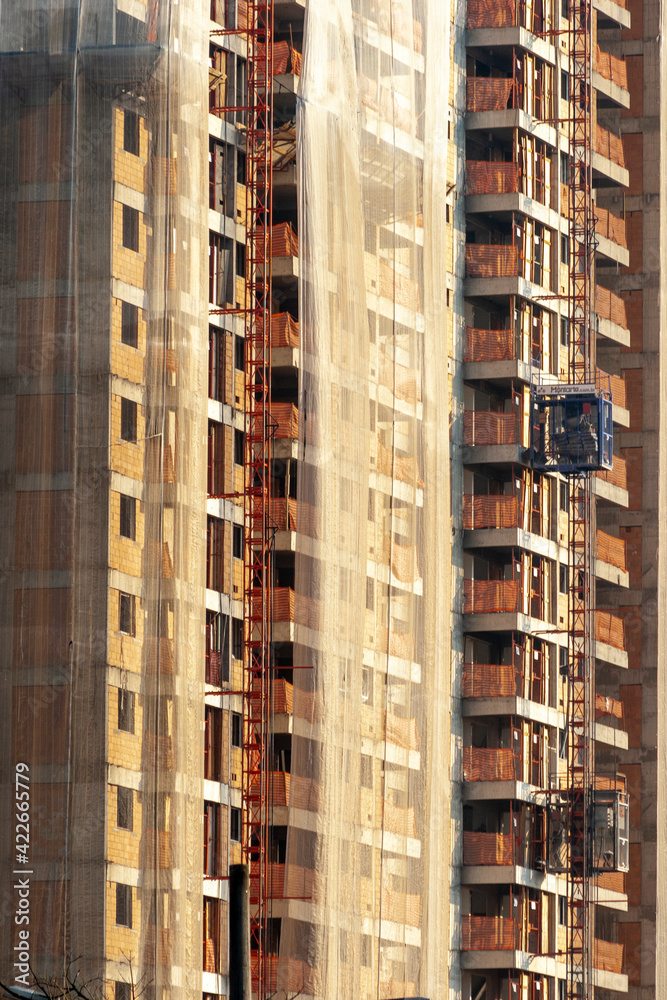 Residential building construction site with net protection and outdoor elevator in Sao Paulo city