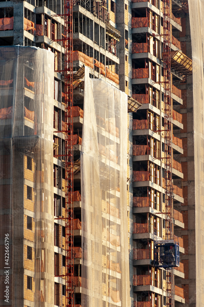 Residential building construction site with net protection and outdoor elevator in Sao Paulo city