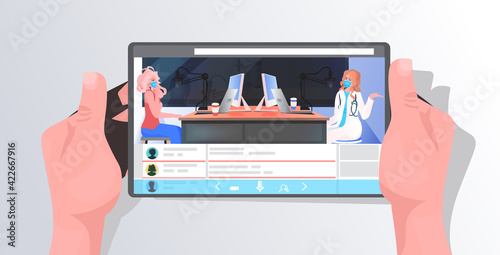 female podcaster and doctor in masks discussing during meeting on tablet screen coronavirus pandemic