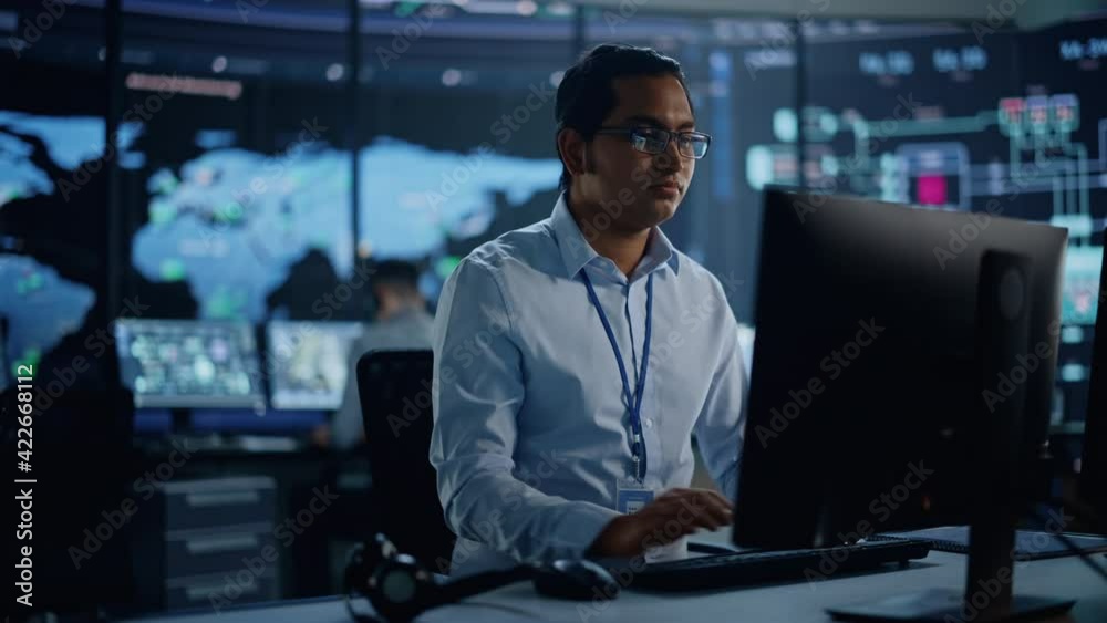 Professional IT Technical Support Specialist and Software Developer Working on Computer in Monitoring Control Room with Digital Screens with Server Data, Blockchain Network and Surveillance Maps. 