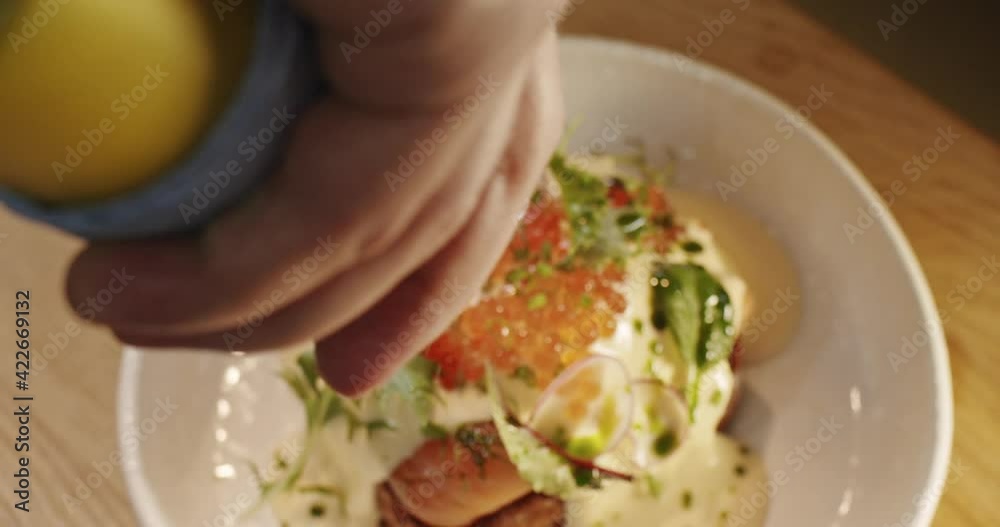 Chef pours healthy green olive oil with herbs on a freshly cooked benedict egg sandwich in slow motion Chef pours healthy green olive oil with herbs on a freshly cooked benedict egg sandwich in slow motion