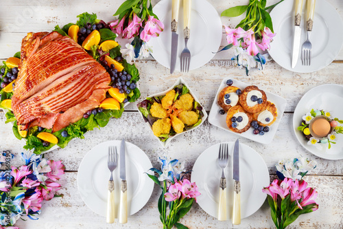 Table setting with baked pork ham on Easter table.