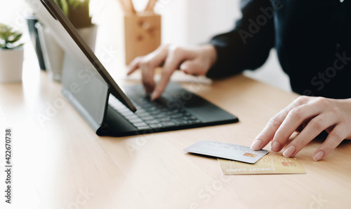 Young woman ues two credit card, using laptop computer. Businesswoman or entrepreneur working at home. Online shopping, e-commerce, internet banking, work from home, lockdown, spending money concept