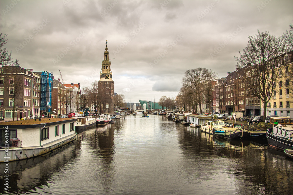 a beatiful canal of amsterdam with a old tower