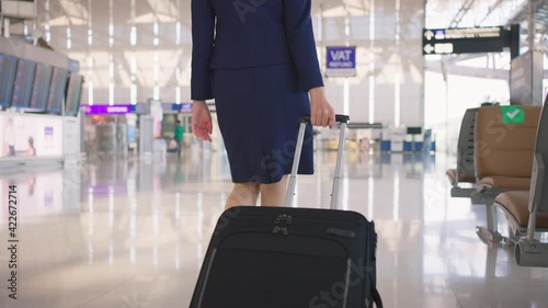 Flight attendant dragging suitcase, walking in passenger terminal. photo