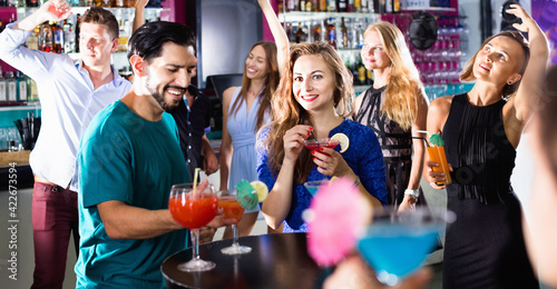 Cheerful man with woman are drinking cocktails on corporate party.