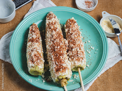 Cooked corn prepared with mayonnaise, cheese and chili powder